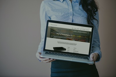 A woman holding a laptop, with Display Technologies displayed on the screen
